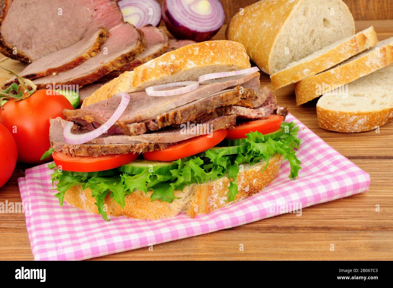 Sandwich di insalata di manzo arrosto con ingredienti su sfondo di legno Foto Stock