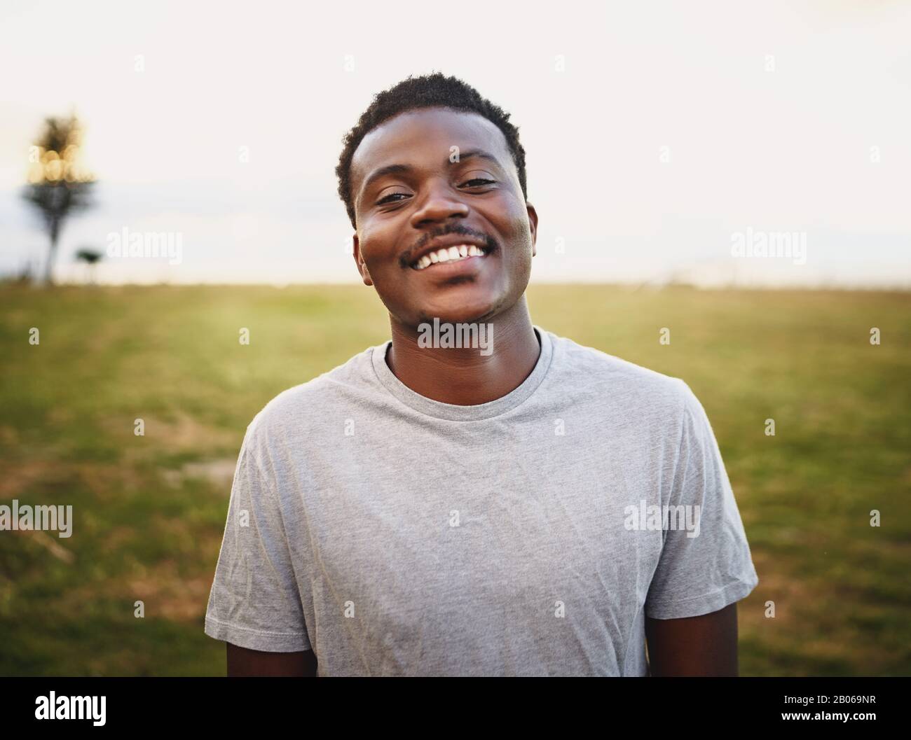 Felice giovane atleta maschile sorridente e guardando la macchina fotografica al parco Foto Stock