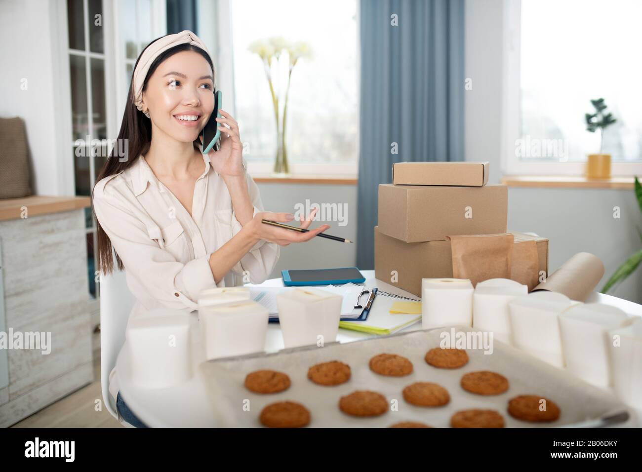 Donna dai capelli scuri che parla dei momenti di lavoro su uno smartphone. Foto Stock