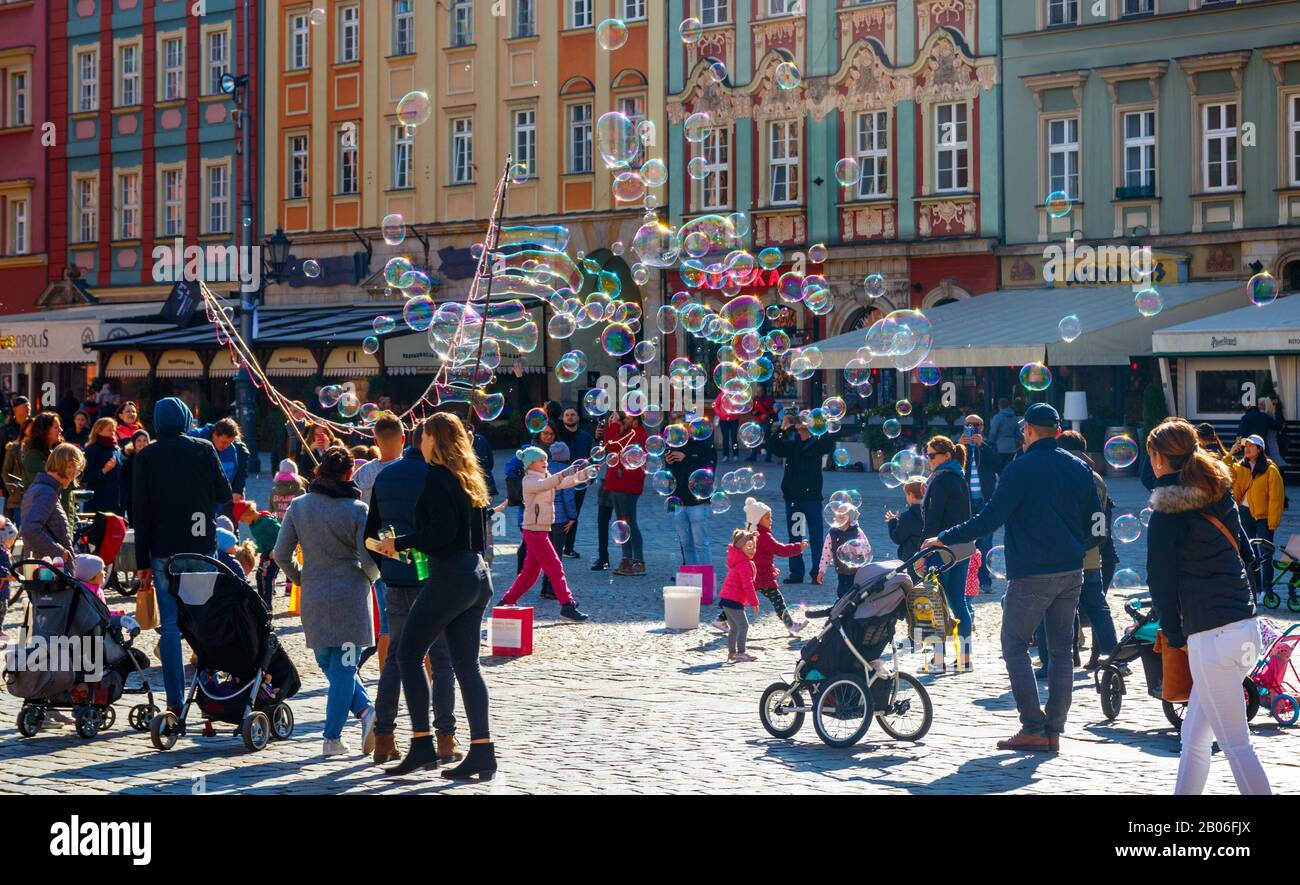 I bambini giocano e si divertono con le bolle di sapone nella vecchia Piazza del mercato in una giornata di sole. Wroclaw, Polonia. Foto Stock