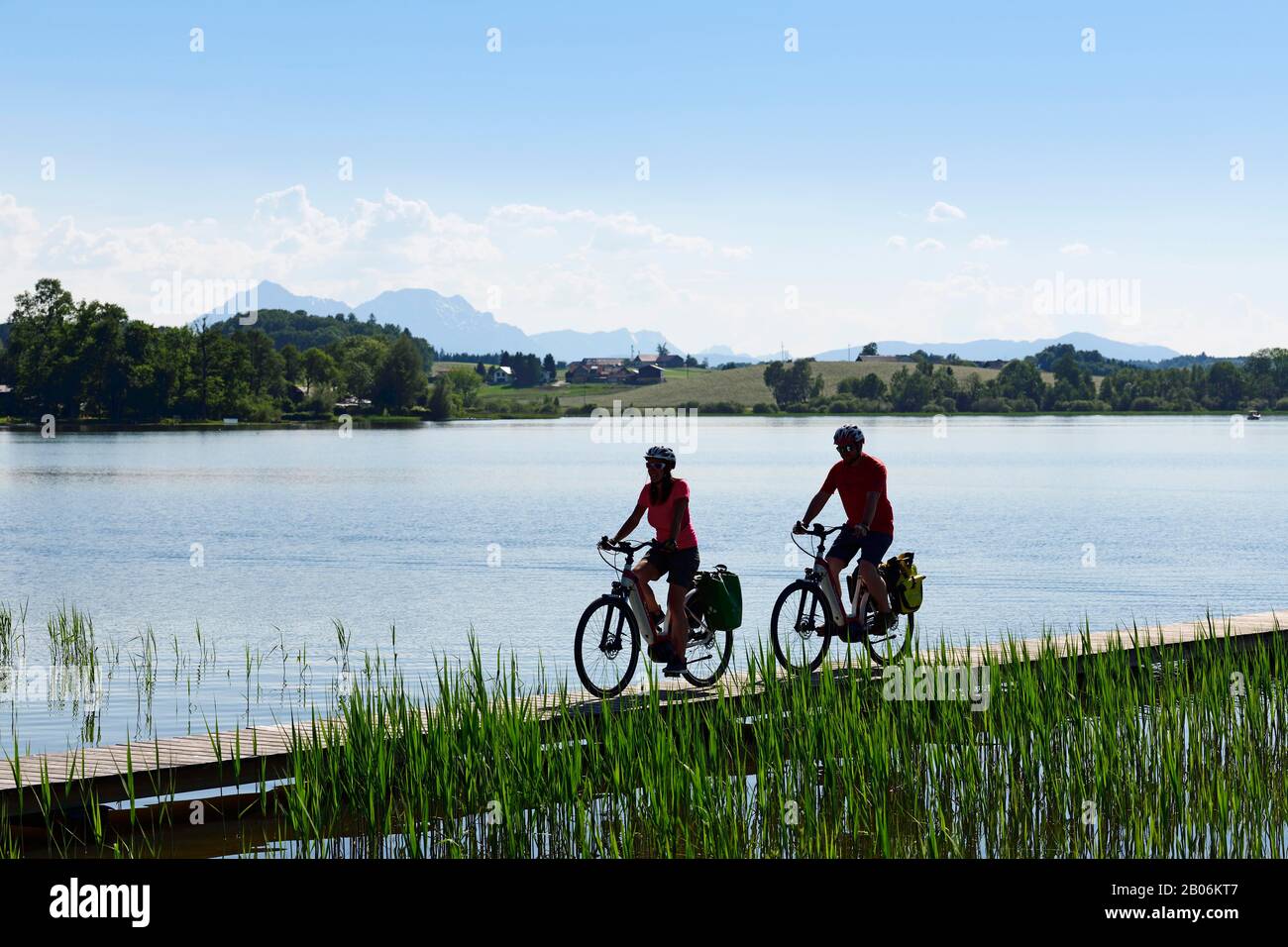 Coppia con bici elettriche a cavallo sulla riva del Lago Wallersee vicino Seebrunn sulla pista ciclabile Via Nova, Salisburgo Lakeland, Salisburgo Land Foto Stock