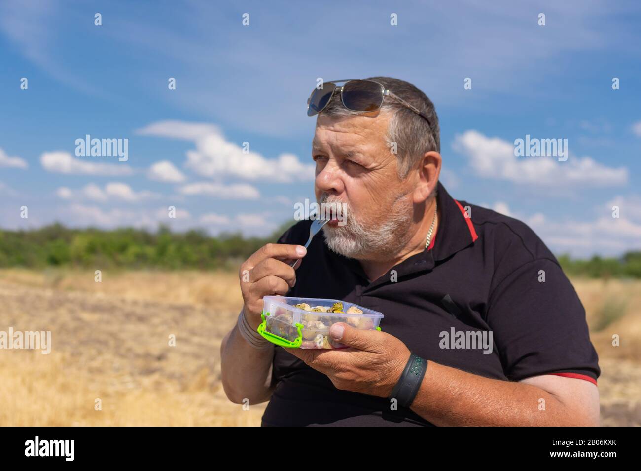 Ritratto di caucasico bearded senior mangiare verdure al vapore all'aperto Foto Stock