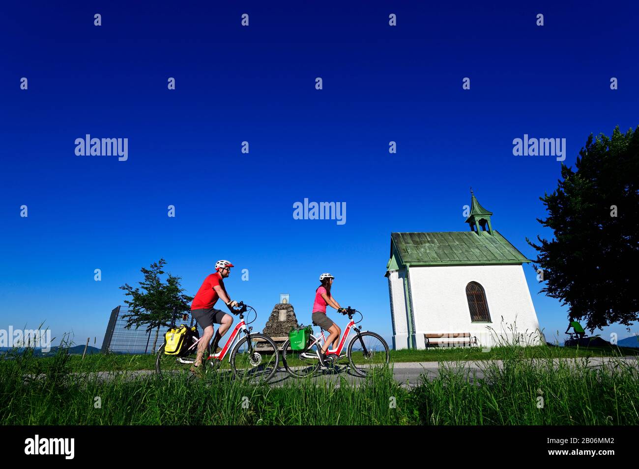 Coppia con bici elettriche di fronte alla faggeta imperiale di Hochberg, Obertrum, Salisburgo Lakeland, Salzburger Land, Austria Foto Stock