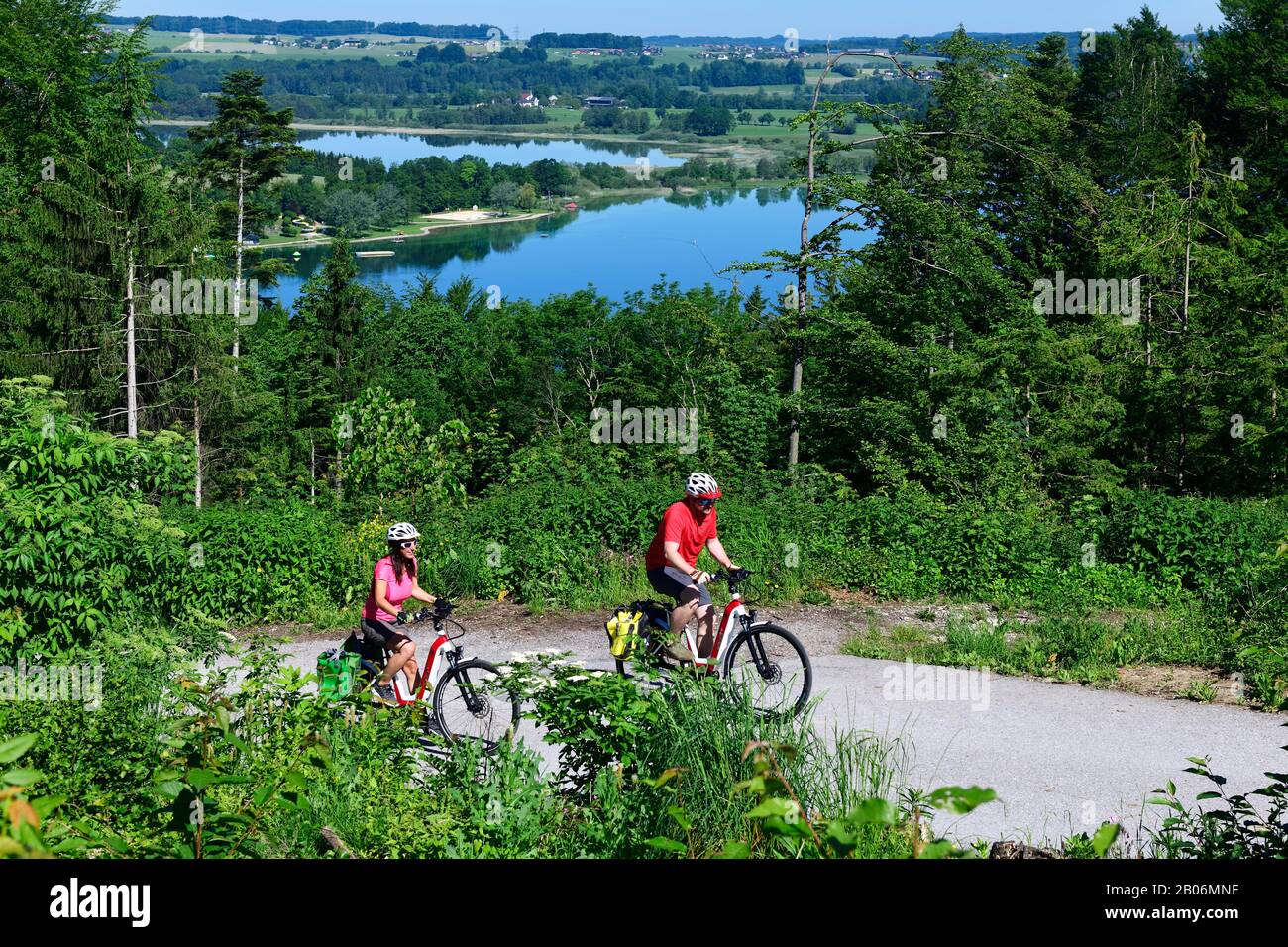 Coppia con bici elettriche a cavallo sopra il lago Mattsee, Ramoos, Mattsee, Salisburgo Lakeland, Salisburgo Land, Austria Foto Stock