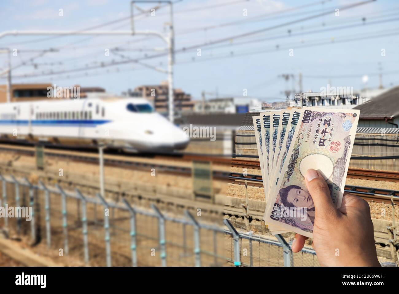 Banconote in mano per il pagamento DI UN treno superveloce Shinkansen in Giappone., Motion Blur di un moderno treno ad alta velocità Shinkansen in Giappone. Foto Stock