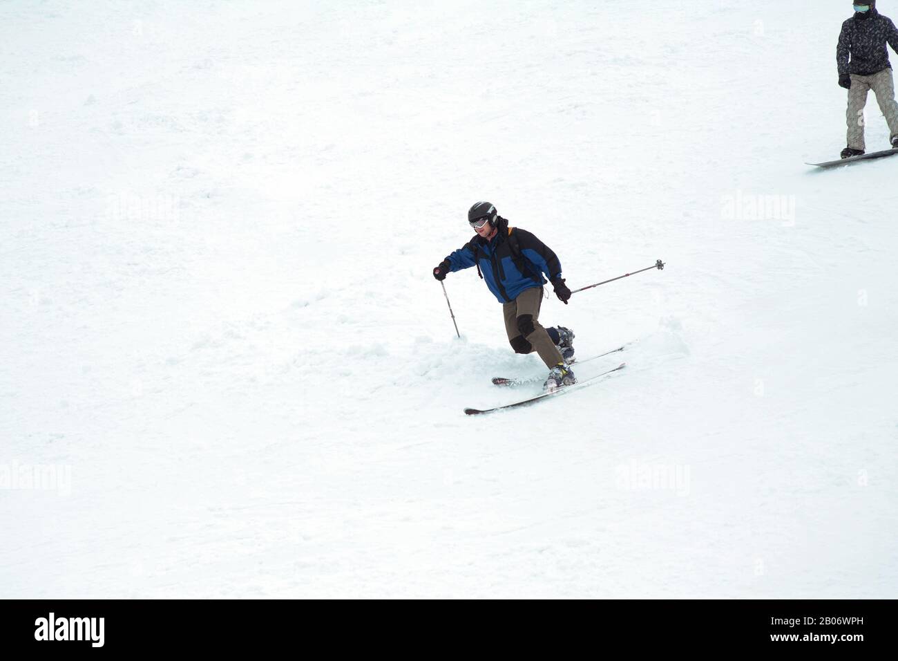 Stazione sciistica. Lo sciatore scende rapidamente su una pista professionale coperta di neve. Un uomo sullo snowboard. Sport professionale. Foto Stock