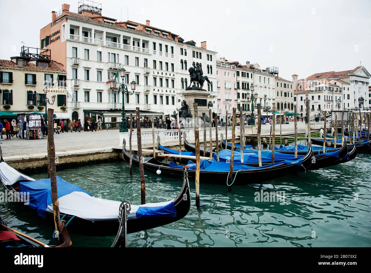 Città Di Venezia, Italia, Europa. Gondole ormeggiate lungo il Canal Grande con coperture blu. Hotel sul Canal Grande in background Foto Stock