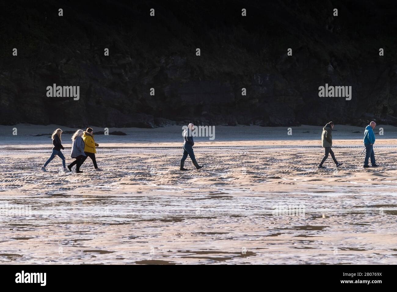 Una vista panoramica delle persone che camminano durante la bassa marea sulla spiaggia di Porth a Newquay in Cornovaglia. Foto Stock