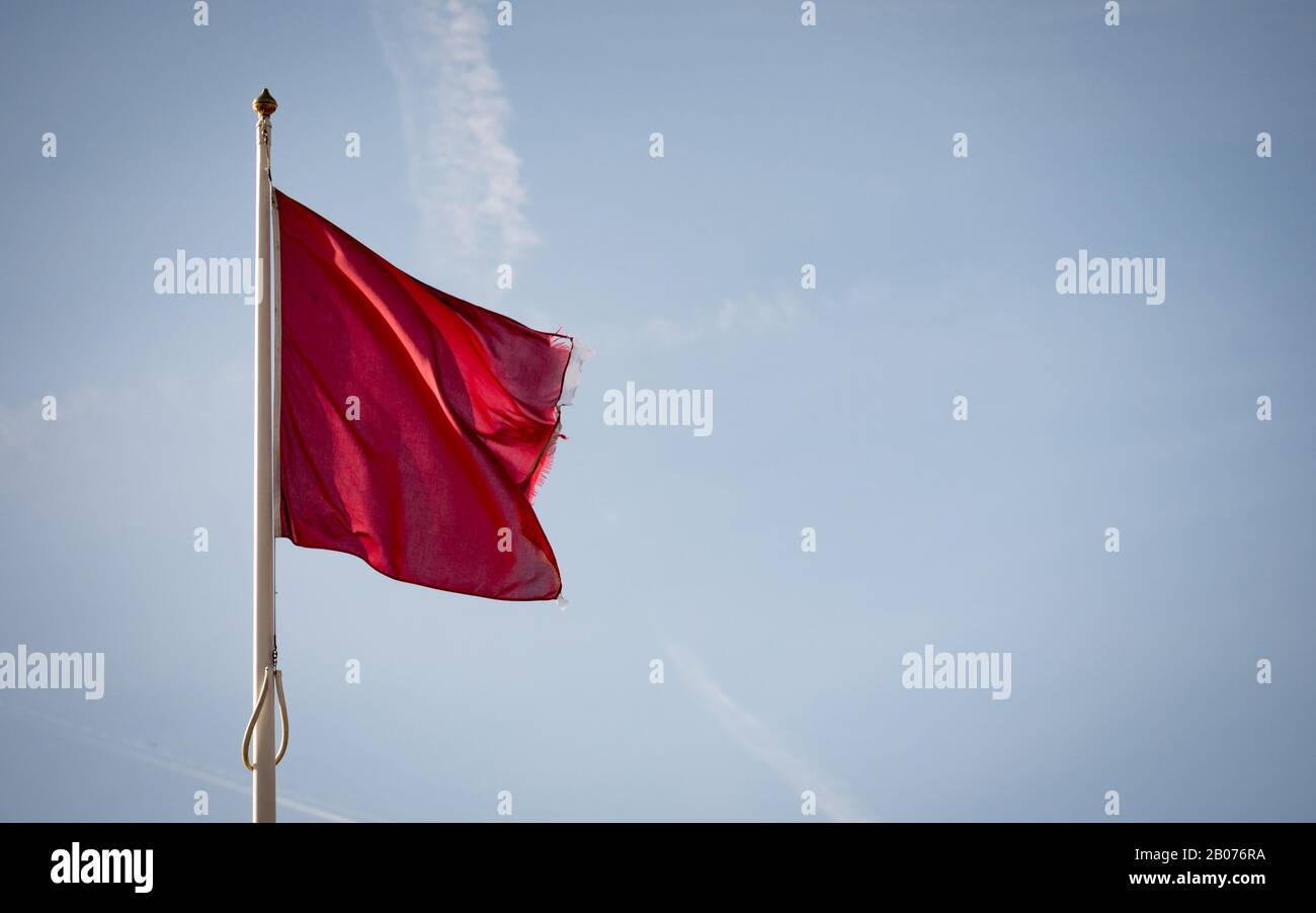 Bandiera della guardia costiera; rossa per il pericolo. Una bandiera che indica che non è sicuro entrare nell'acqua; impostare contro lo spazio di copia cielo blu. Foto Stock