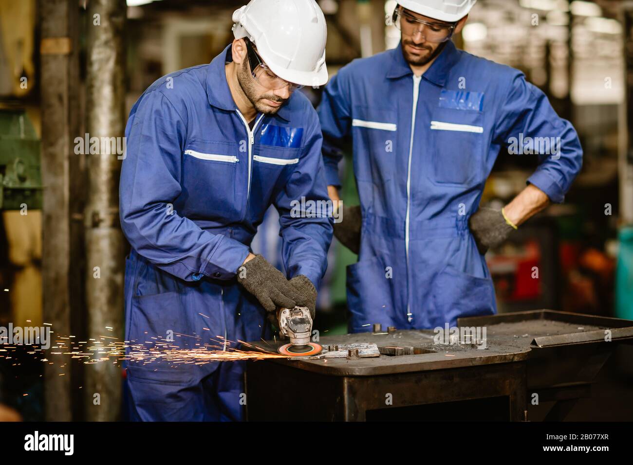 formazione dei lavoratori di alto livello e controllo del giovane tirocinante a utilizzare l'attrezzo per la sicurezza nel lavoro ndustriale tagliato in acciaio. Foto Stock