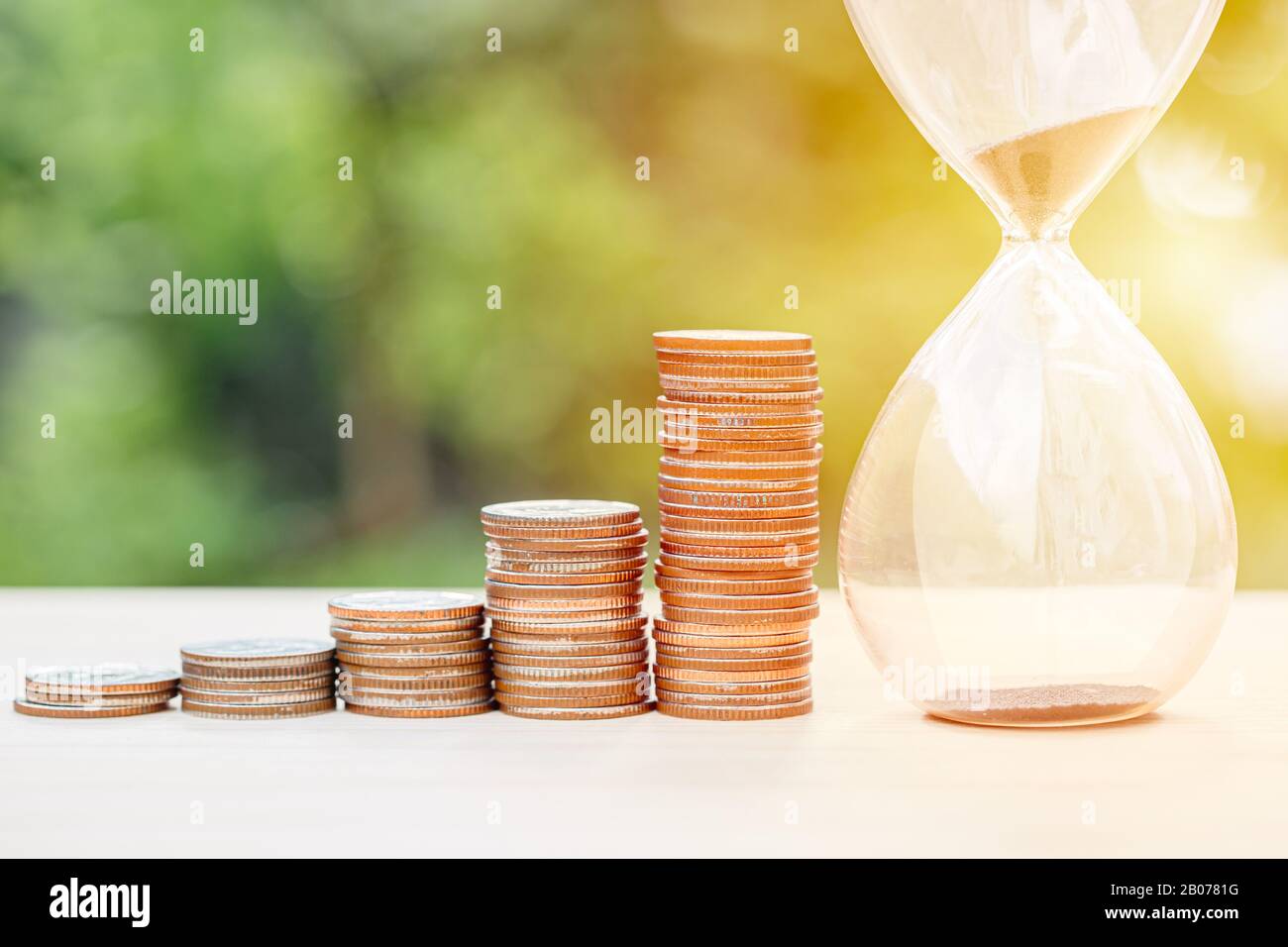 denaro times memoria concetto, monete stack con sabbia clessidra Foto Stock