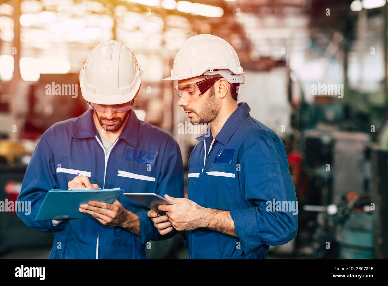 Il lavoro di squadra dei tecnici collabora con i lavoratori per controllare la sicurezza della macchina di fabbrica e parlare insieme. Foto Stock