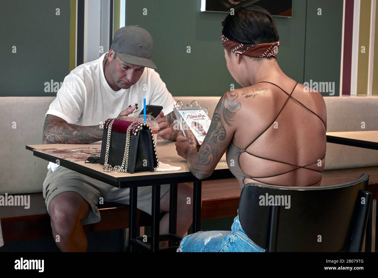 Donna top senza schienale, tracolla e tatuaggio braccio Foto Stock