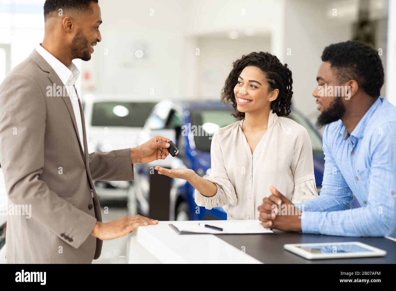 Il Responsabile Che Dà La Chiave Ai Coniugi Che Si Trovano In Ufficio Di Autonoleggio Foto Stock