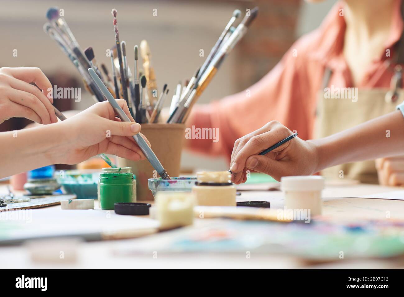 Primo piano dei bambini con vernici a pennello e ad acquerello per dipingere  le immagini al tavolo Foto stock - Alamy
