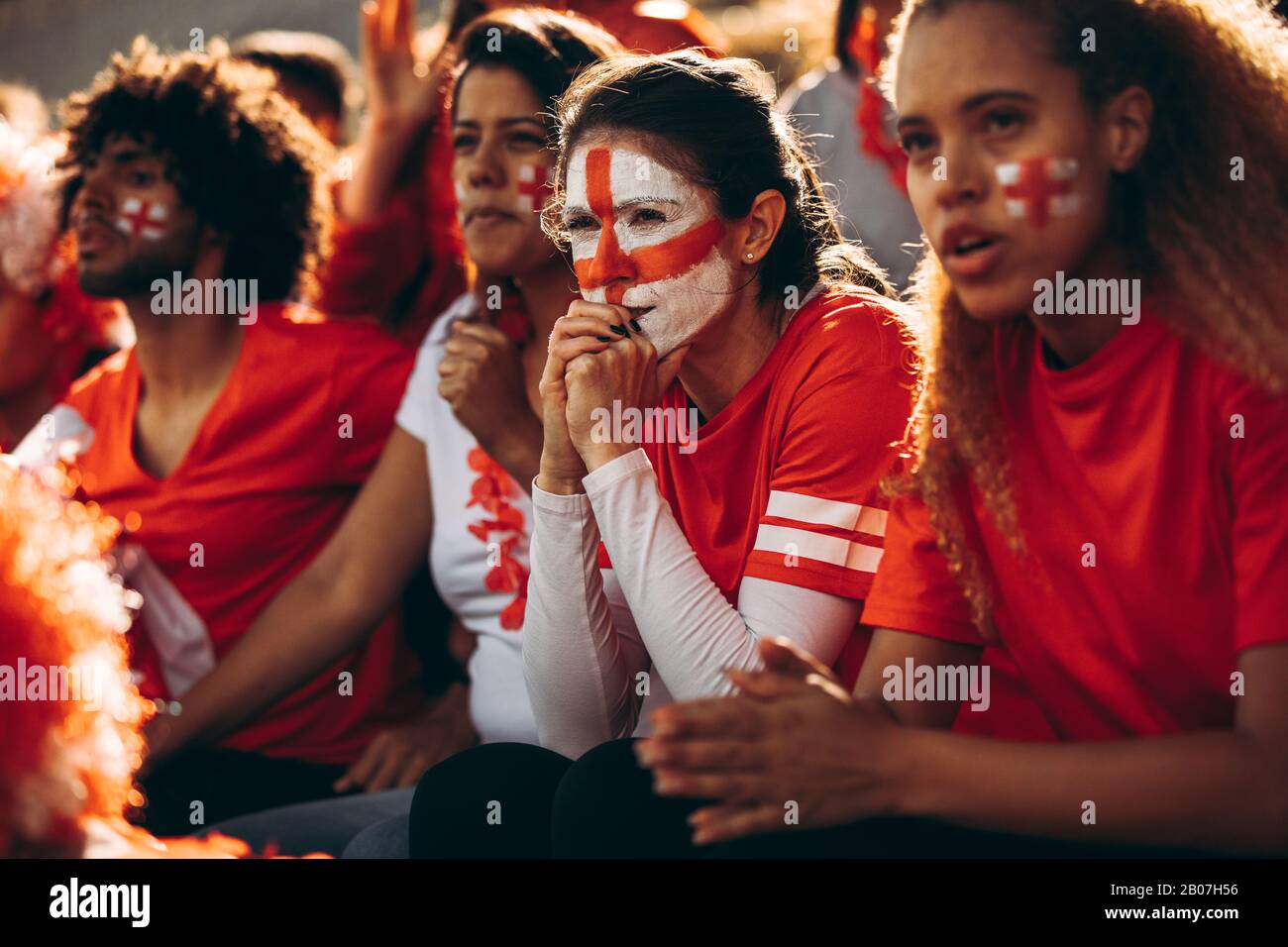 Ansioso guardare gli appassionati di calcio inglese guardare la partita allo stadio. Gruppo di tifosi della squadra di calcio inglese che guardano la partita da vicino dagli stand Foto Stock
