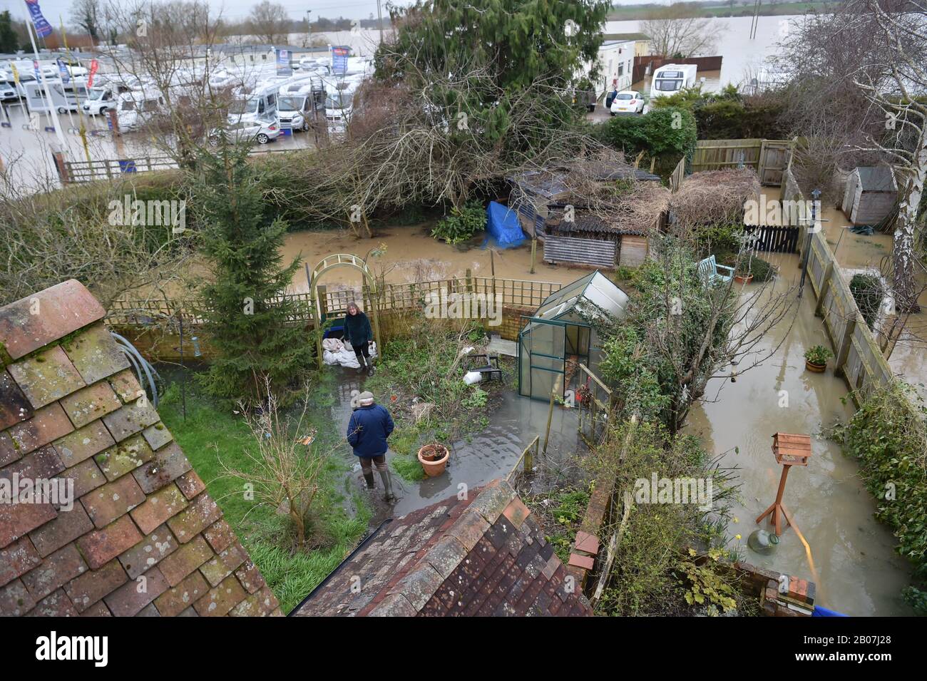Le persone che controllano l'acqua nelle loro giardini posteriori, come le pompe e le barriere alluvionali aiutano a mantenere l'acqua dalle case allagate a Gloucester Road a Tewkesbury, Gloucestershire, dopo il periodo successivo a Storm Dennis. Foto Stock