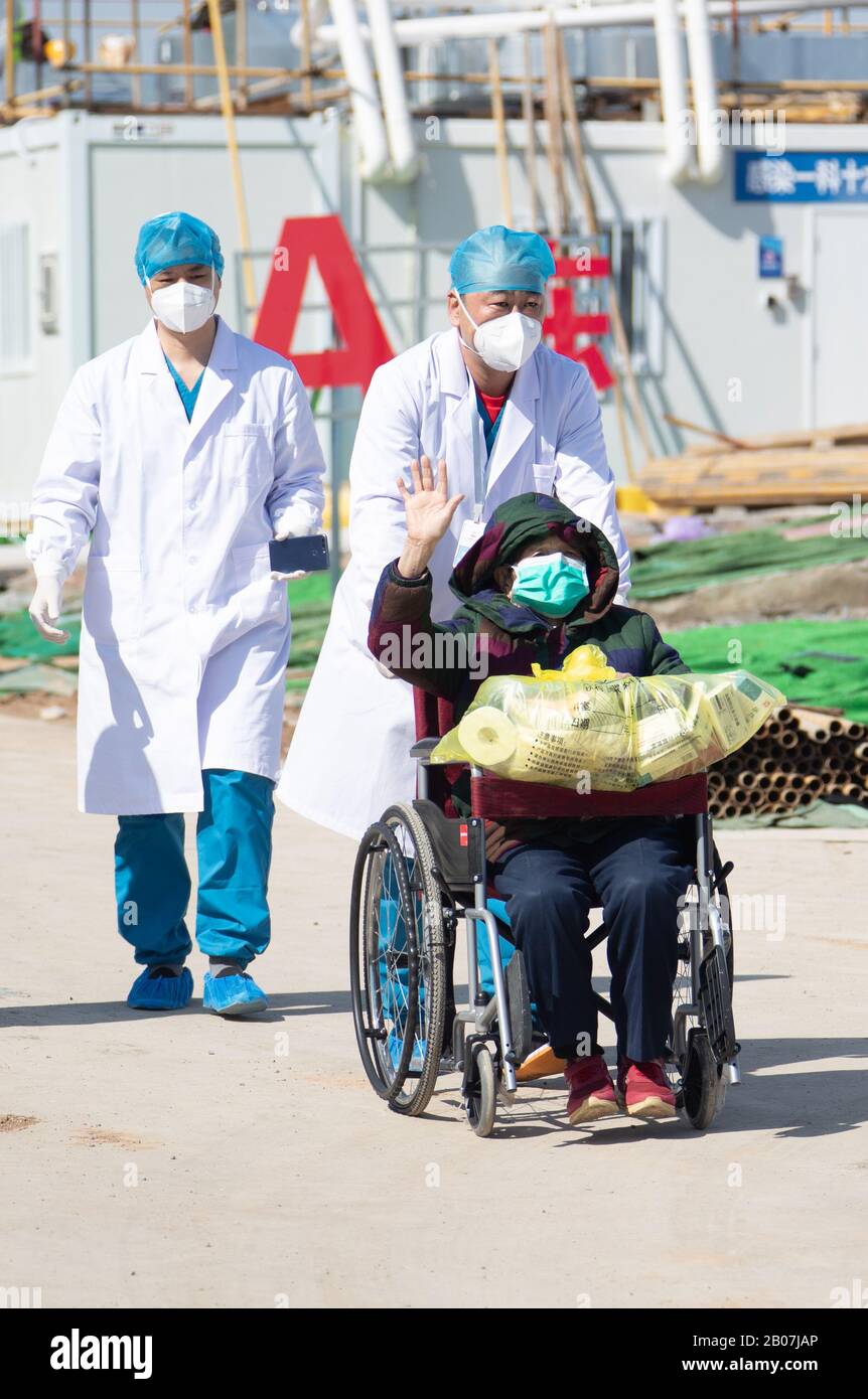 Una donna cinese anziana che è stata infettata con il nuovo coronavirus e la polmonite e ha appena recuperato le onde alle persone quando sta lasciando Wuhan Leishens Foto Stock