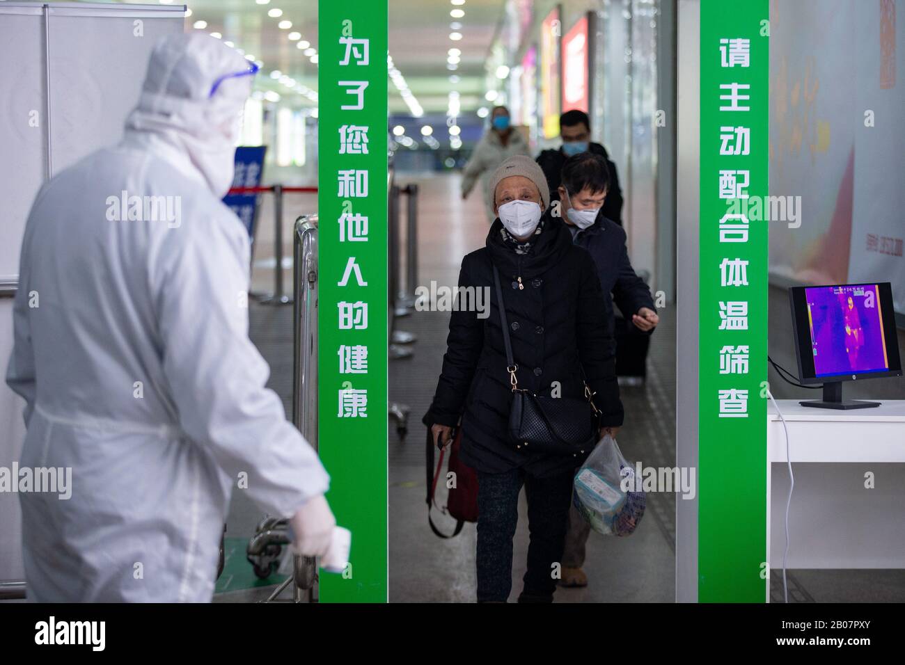 Gli operatori sanitari cinesi ben attrezzati controllano le temperature del corpo dei passeggeri all'uscita per prevenire il nuovo coronavirus e la polmonite sulla loro A. Foto Stock