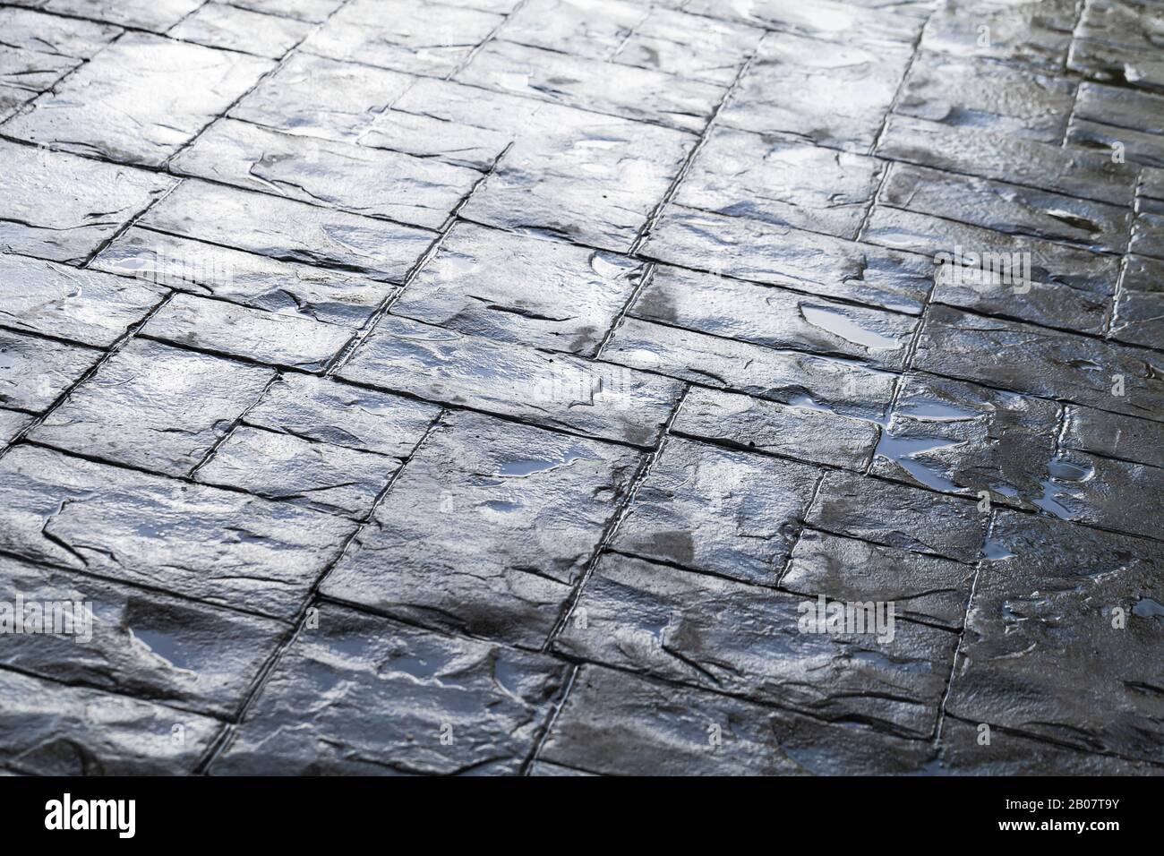 Pavimentazione stradale in ciottoli grigio bagnato lucido, texture foto di sfondo Foto Stock