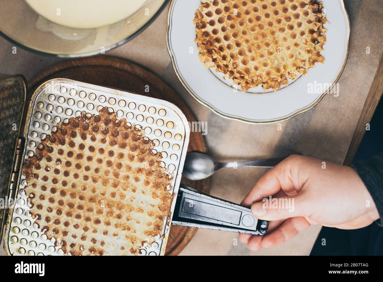Chiudete le mani sulle donne che cucinano waffle fatti in casa su un ferro da stiro vintage Foto Stock