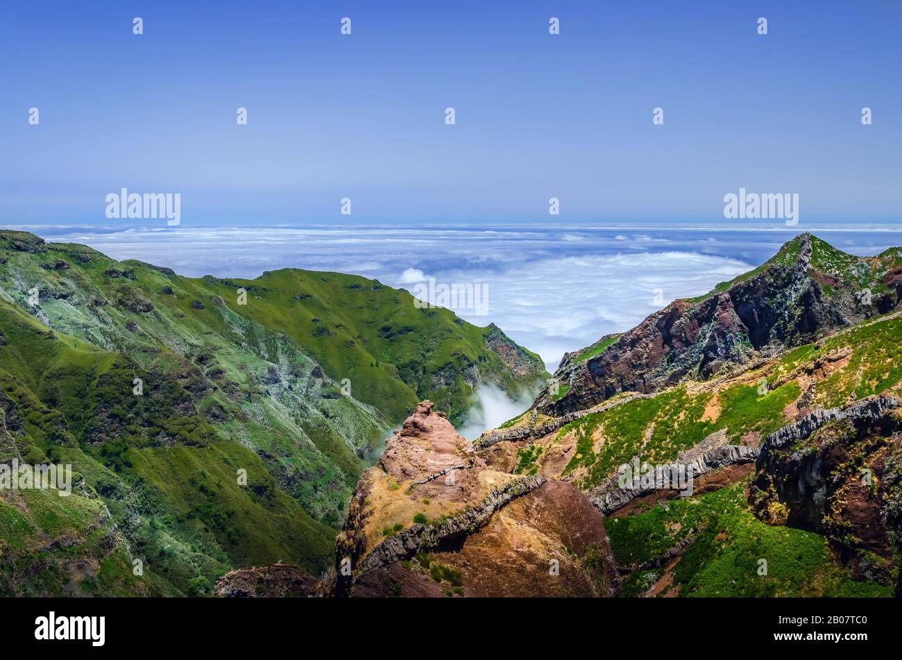 Sfondo orizzontale con il magnifico paesaggio dell'isola di Madeira. Vista dall'alto sulla catena montuosa coperta da verde vegetazione lussureggiante e su densa nuvola Foto Stock