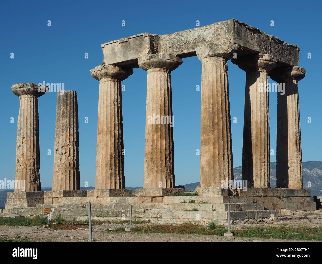 Colonne doriche del Tempio arcaico ad Apollo a Corinto, Peloponneso, Grecia contro un cielo blu Foto Stock