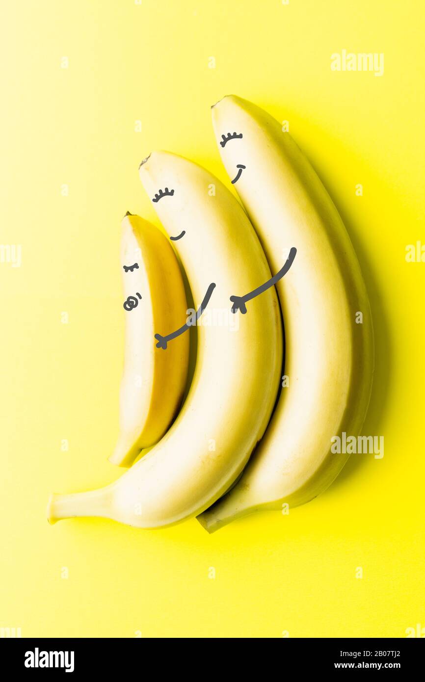 Immagine concettuale di due grandi genitori di banane che detengono una piccola banana del bambino, che assomiglia alla genitorialità e all'amore Foto Stock