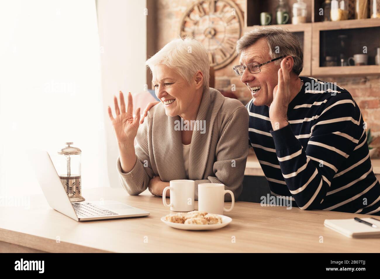 Felice senior coppia che guarda il notebook schermo in cucina e sventolare Foto Stock