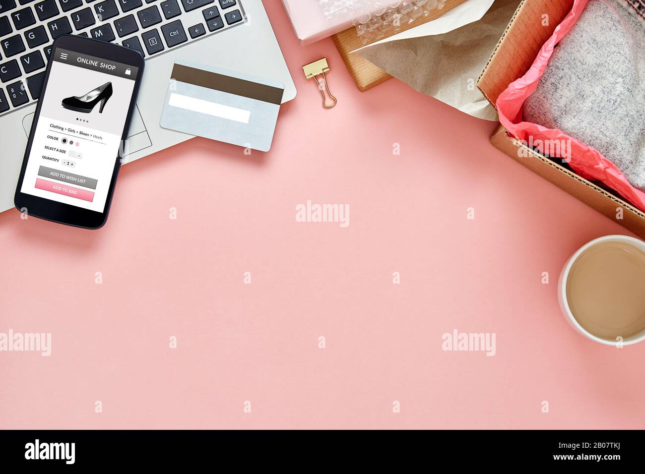 Negozio online per le donne sullo schermo dello smartphone sul tavolo da ufficio rosa con spazio per le copie. Concetto di intestazione Hero. Vista dall'alto. Foto Stock