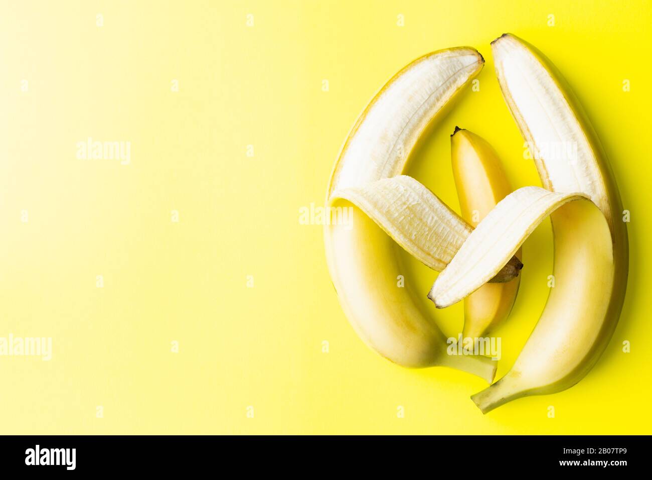 Immagine concettuale di due grandi genitori di banane che detengono una piccola banana del bambino, che assomiglia alla genitorialità e all'amore Foto Stock