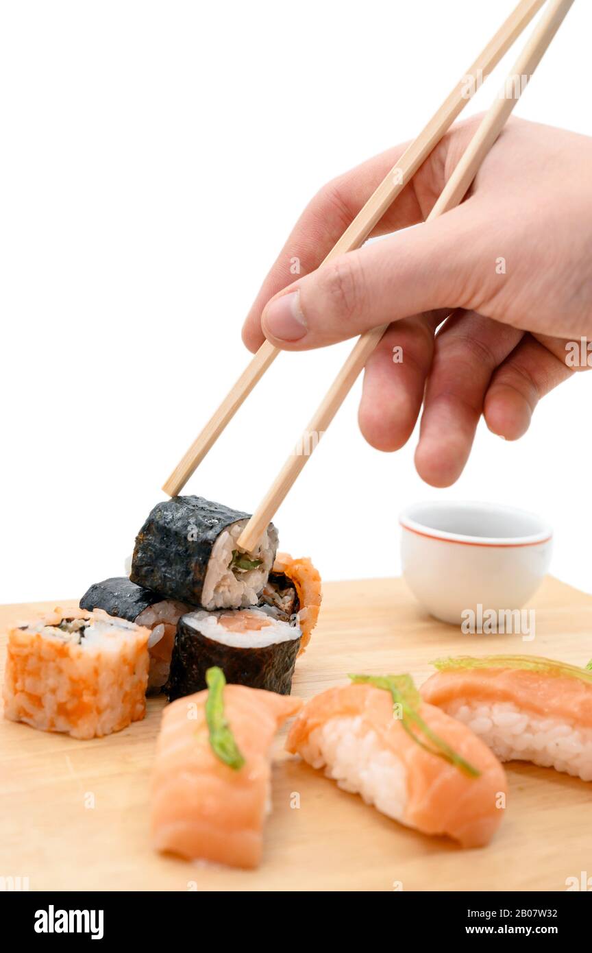 Il ristorante Giapponese serve sushi roll a mano con bastoni su sfondo bianco isolato. Foto Stock