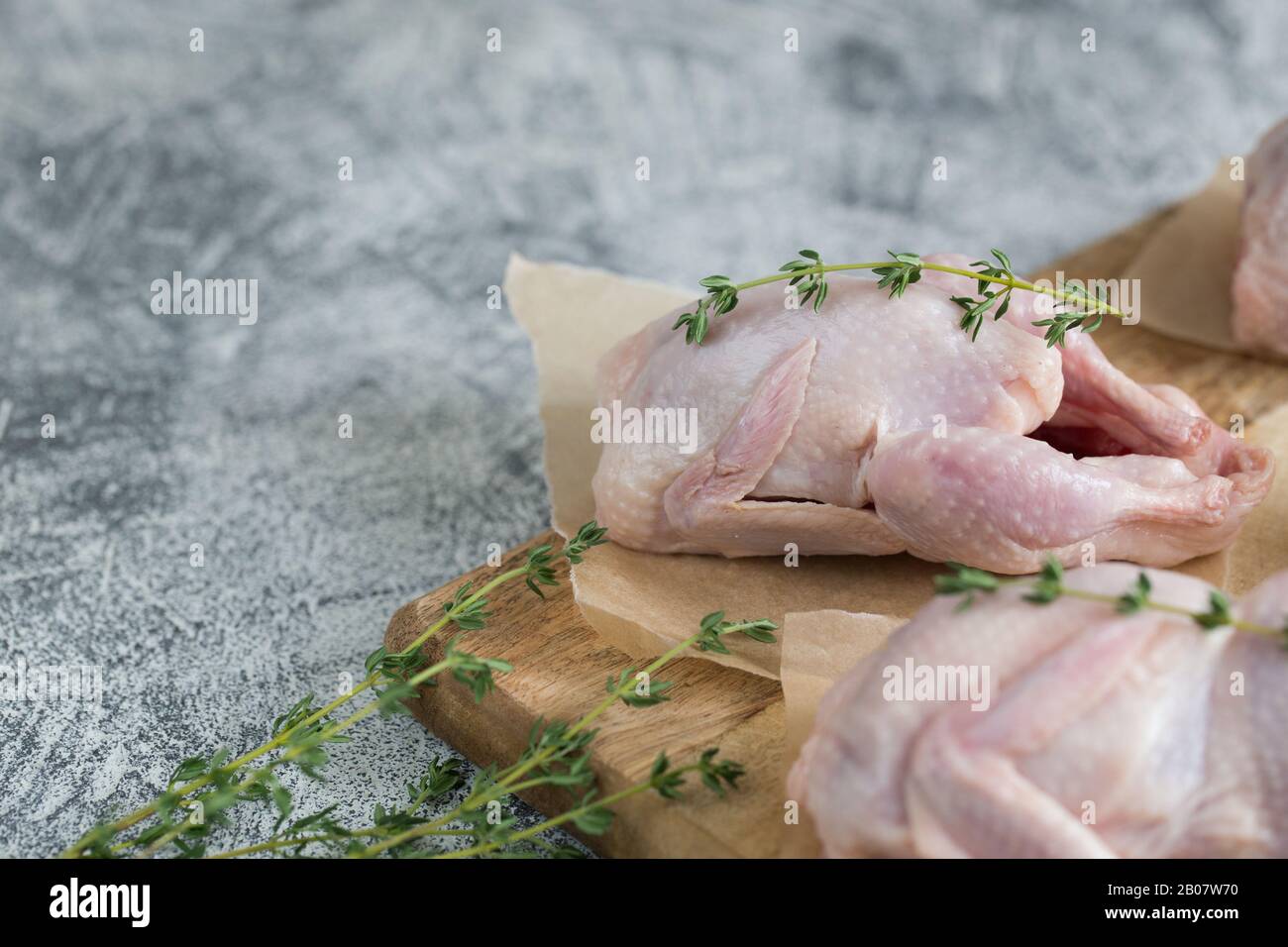 Materie non cotti quaglie. carne cruda quaglie pronte per la cottura su un tagliere con spazio copia/ Foto Stock