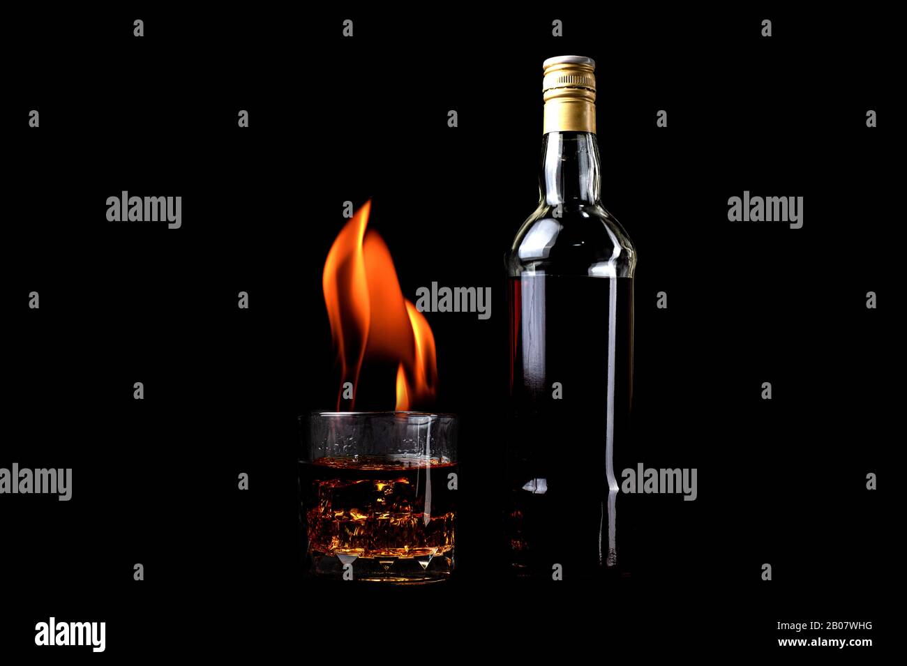 Bottiglie di liquore e vetro whiskey con fuoco e fiamma su sfondo nero Foto Stock