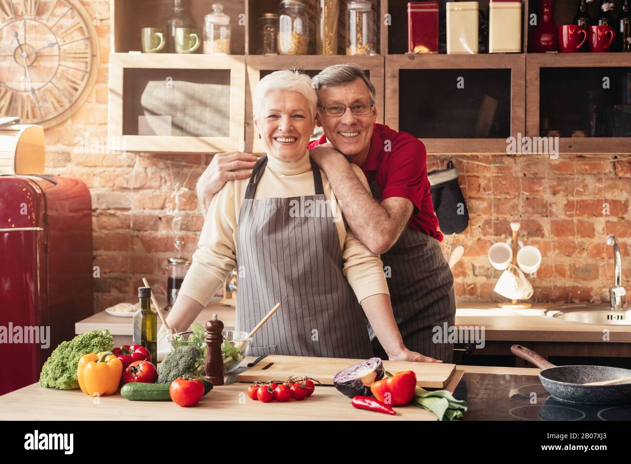Coppia sorridente anziani che si posano insieme in cucina interna Foto Stock