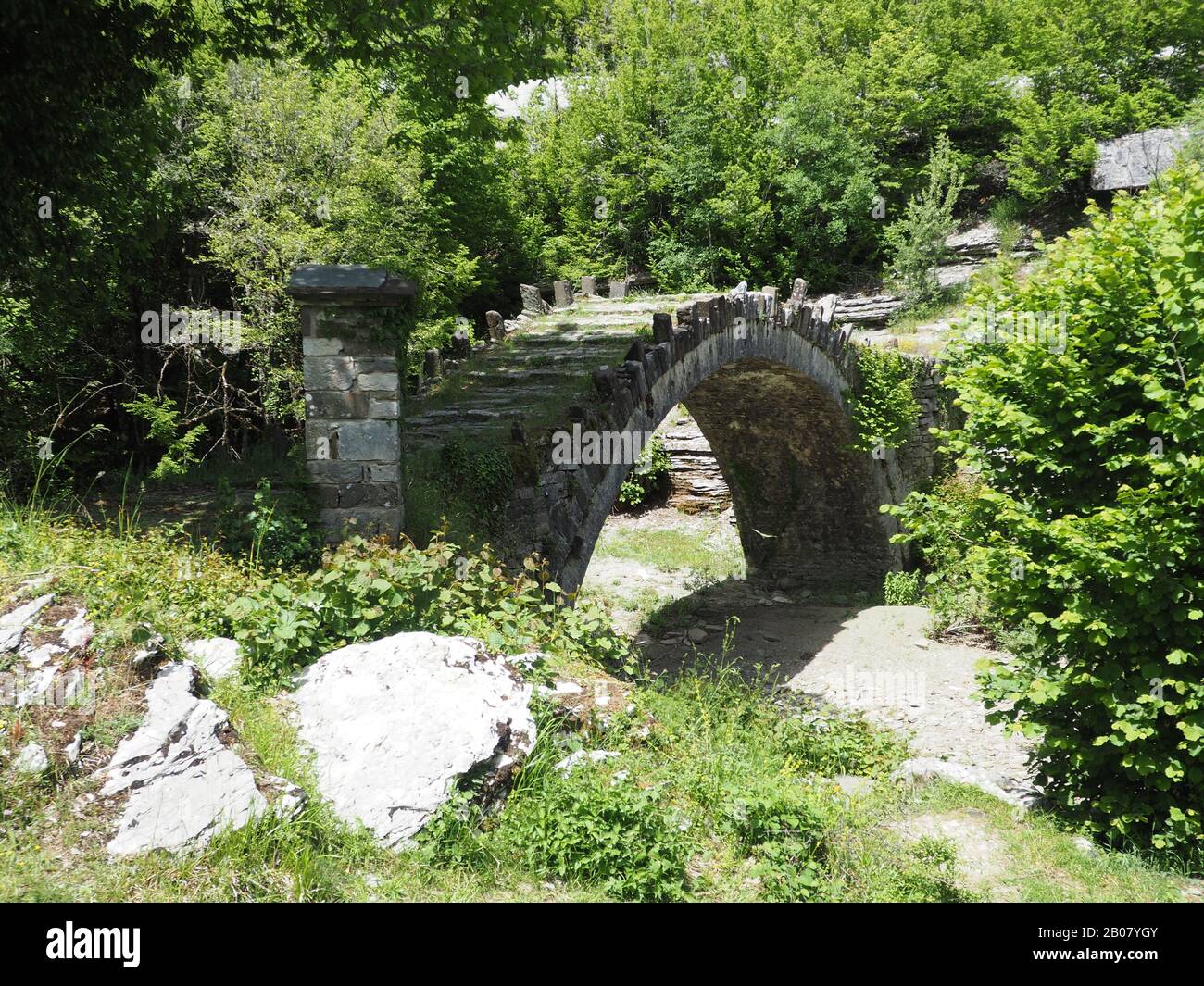 Vecchio ponte in pietra ad arco singolo su un letto di fiume secco chiamato Arkouda o Bear Bridge. Vicino al villaggio di Dilofo nel centro di Zagori, Ioannina, Grecia Foto Stock