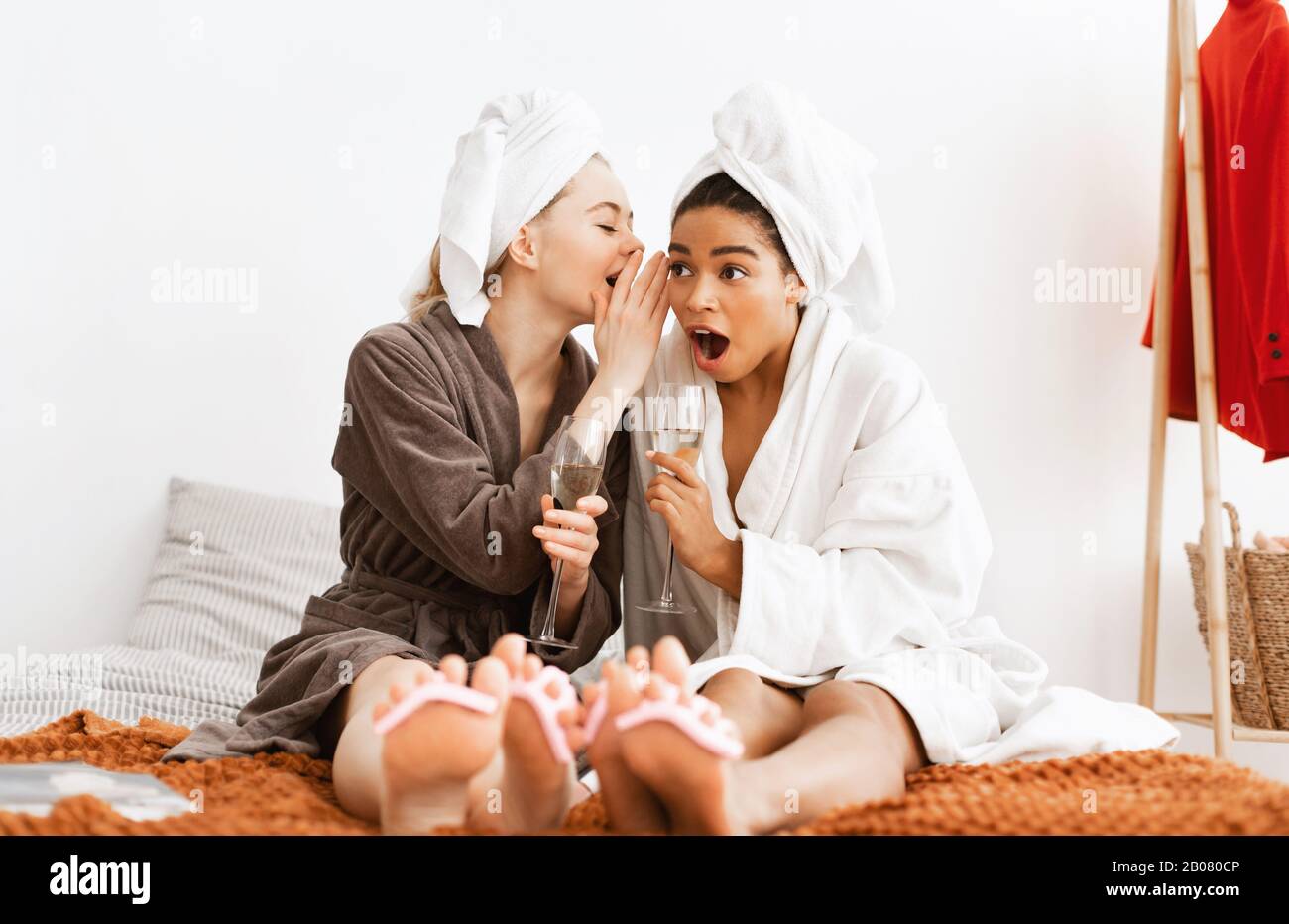 Allegre girlfriends multietnici che condividono pettegolezzi mentre fanno pedicure Foto Stock