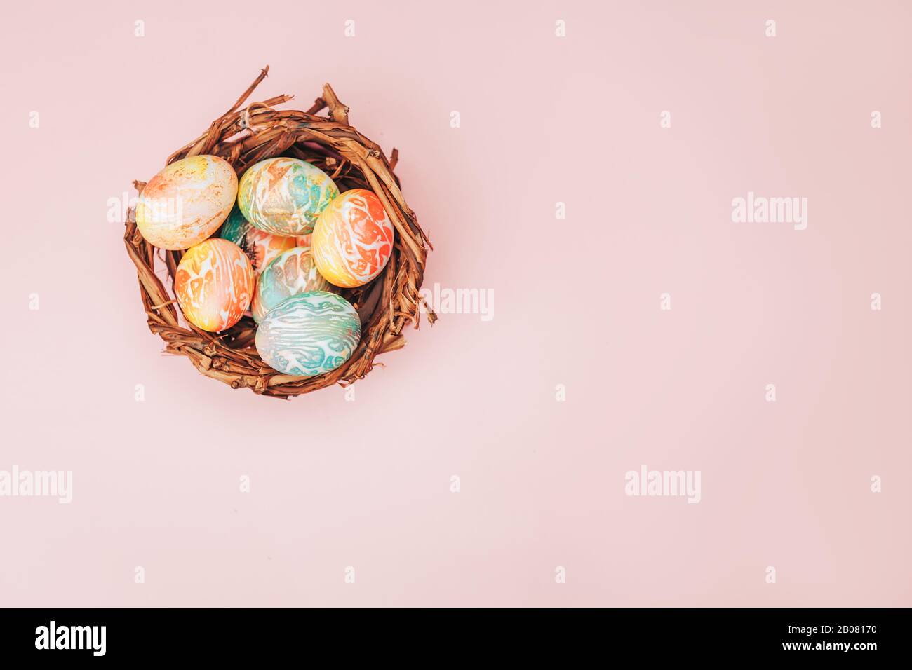Colofy uova di pasqua in nido su sfondo color rosa pastello, copia spazio. Foto Stock