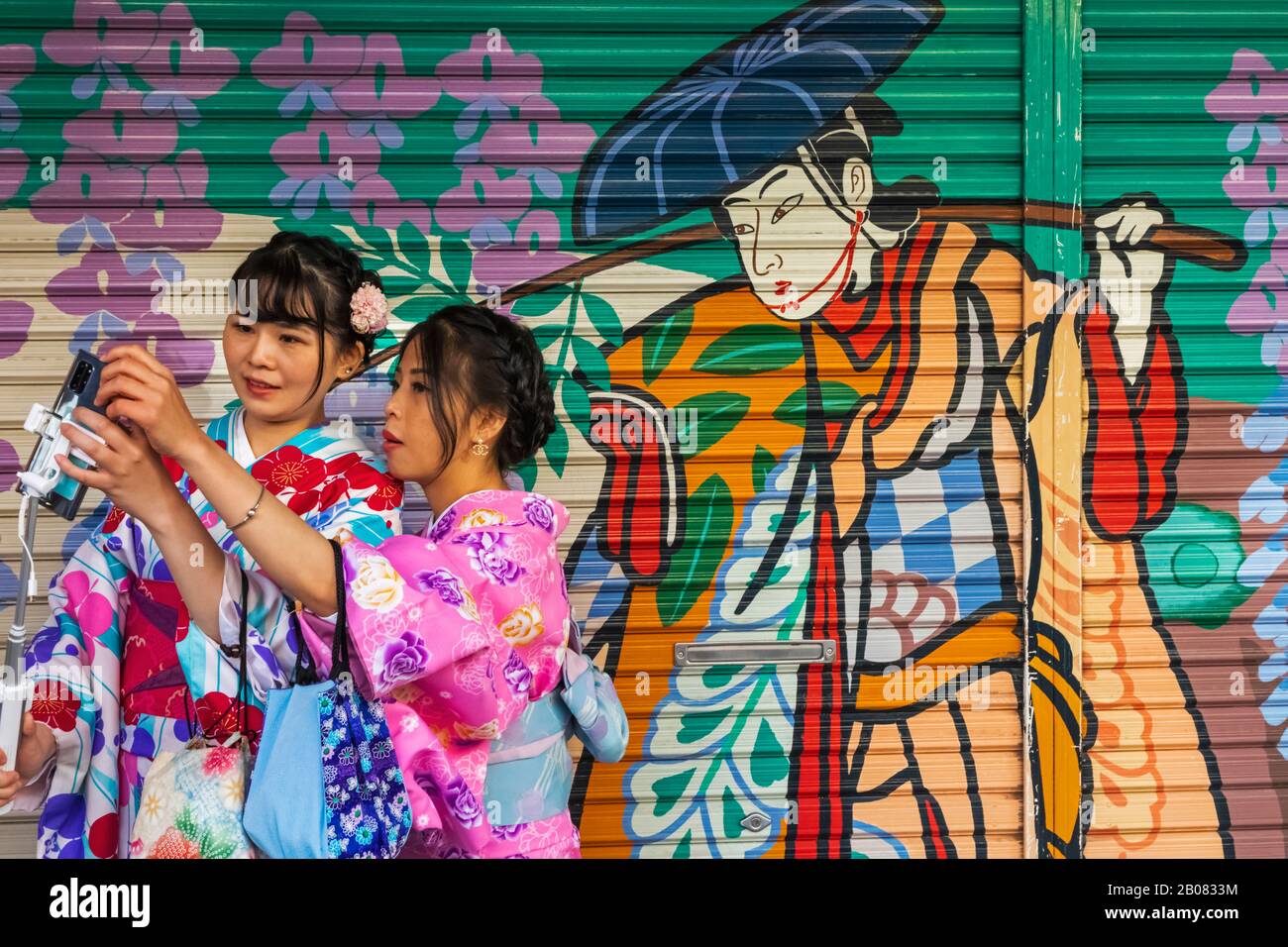 Giappone, Honshu, Tokyo, Asakusa, Due Donne In Kimono Scattare Foto Di Selfie Di Fronte Alla Coloratissima Pittura Dell'Otturatore Del Negozio Foto Stock