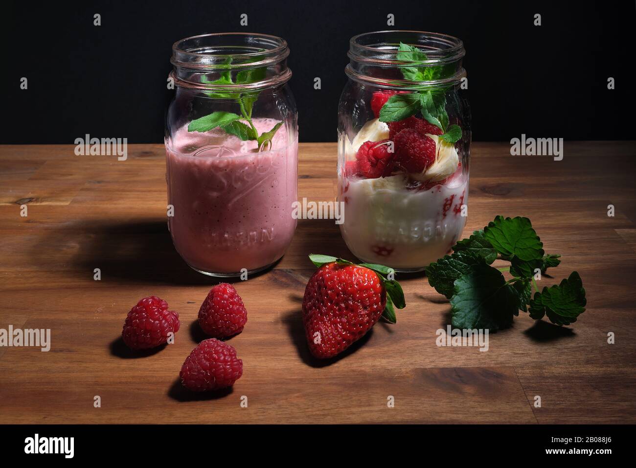 frullato di fragola disposto su un piatto di legno con sfondo nero, spazio pubblicitario Foto Stock