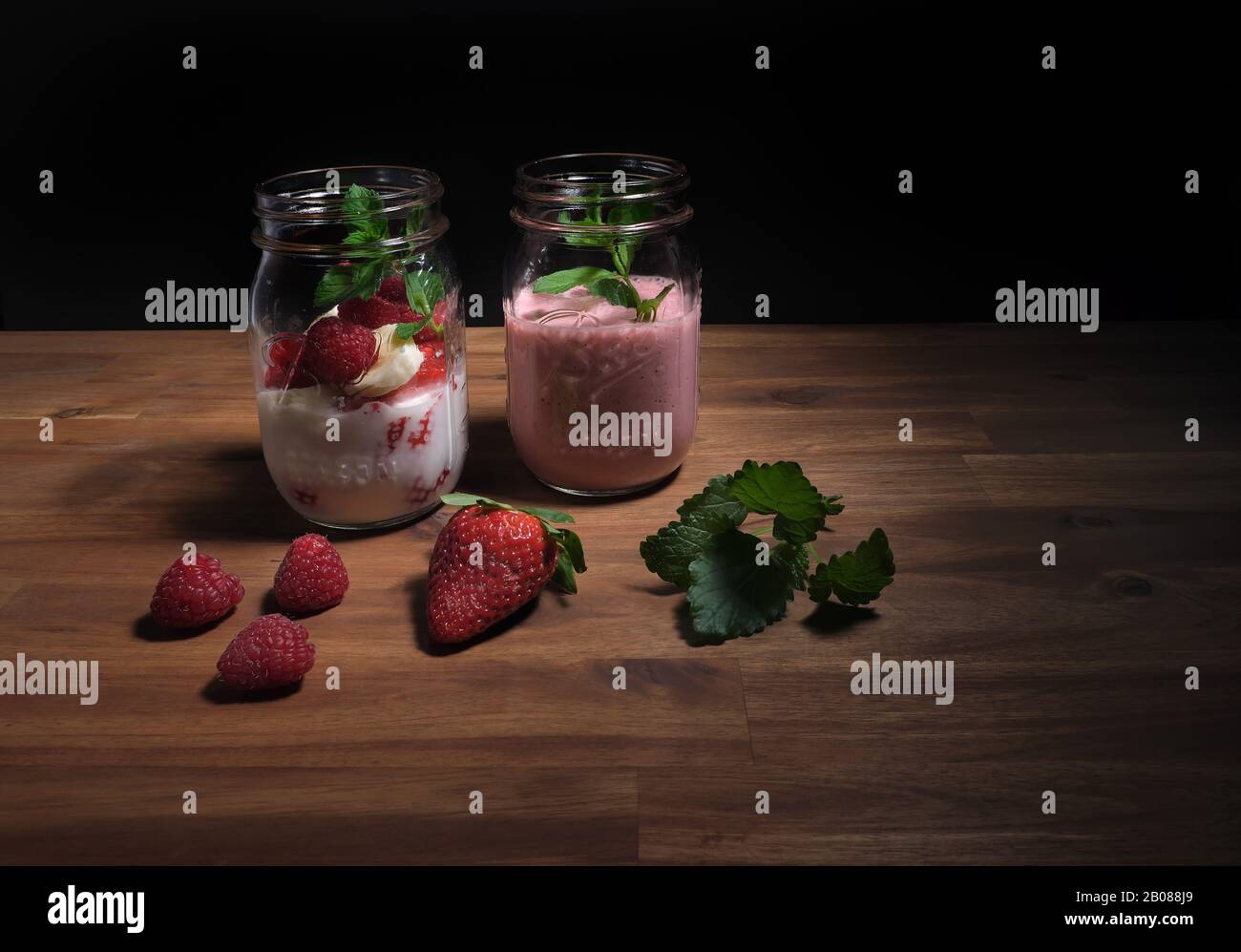 frullato di fragola disposto su un piatto di legno con sfondo nero, spazio pubblicitario Foto Stock