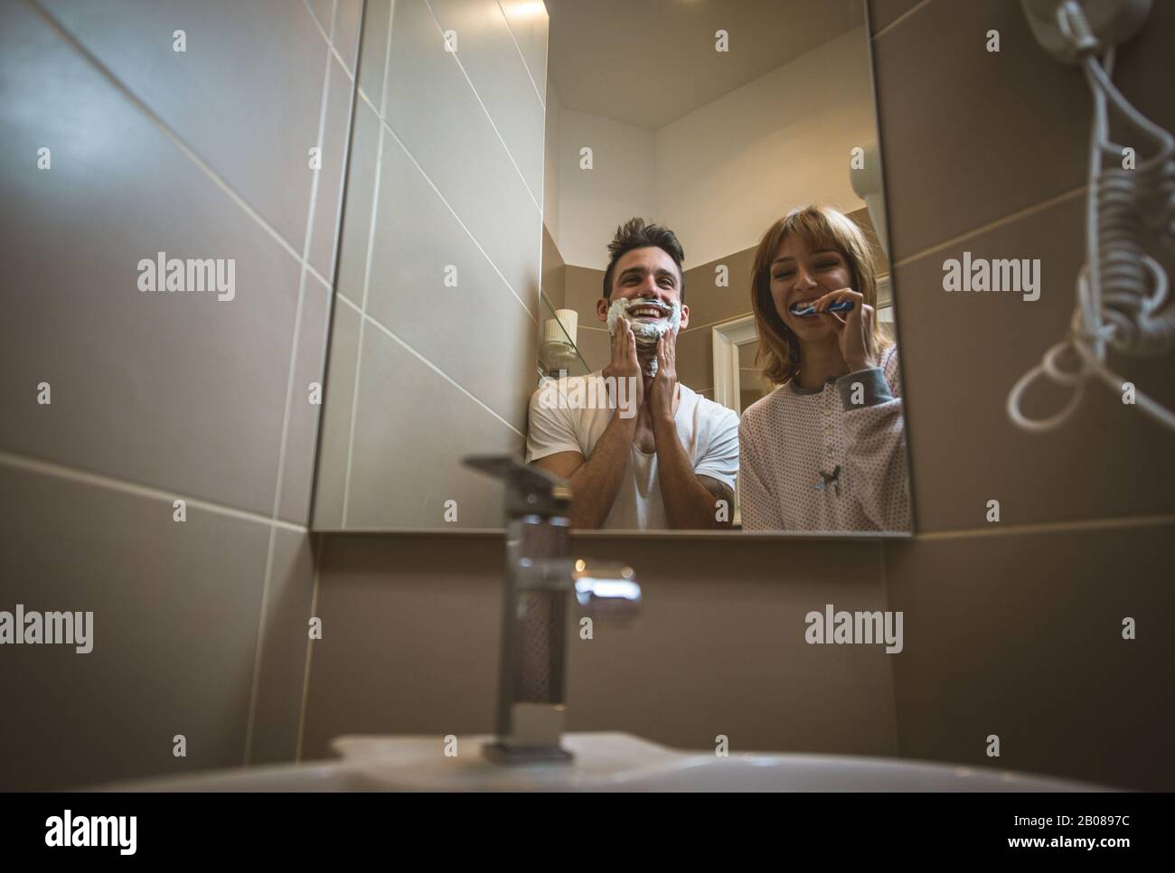 Routine di coppia del mattino. Uomo e donna che condividono il bagno. Barba e denti spazzolanti Foto Stock