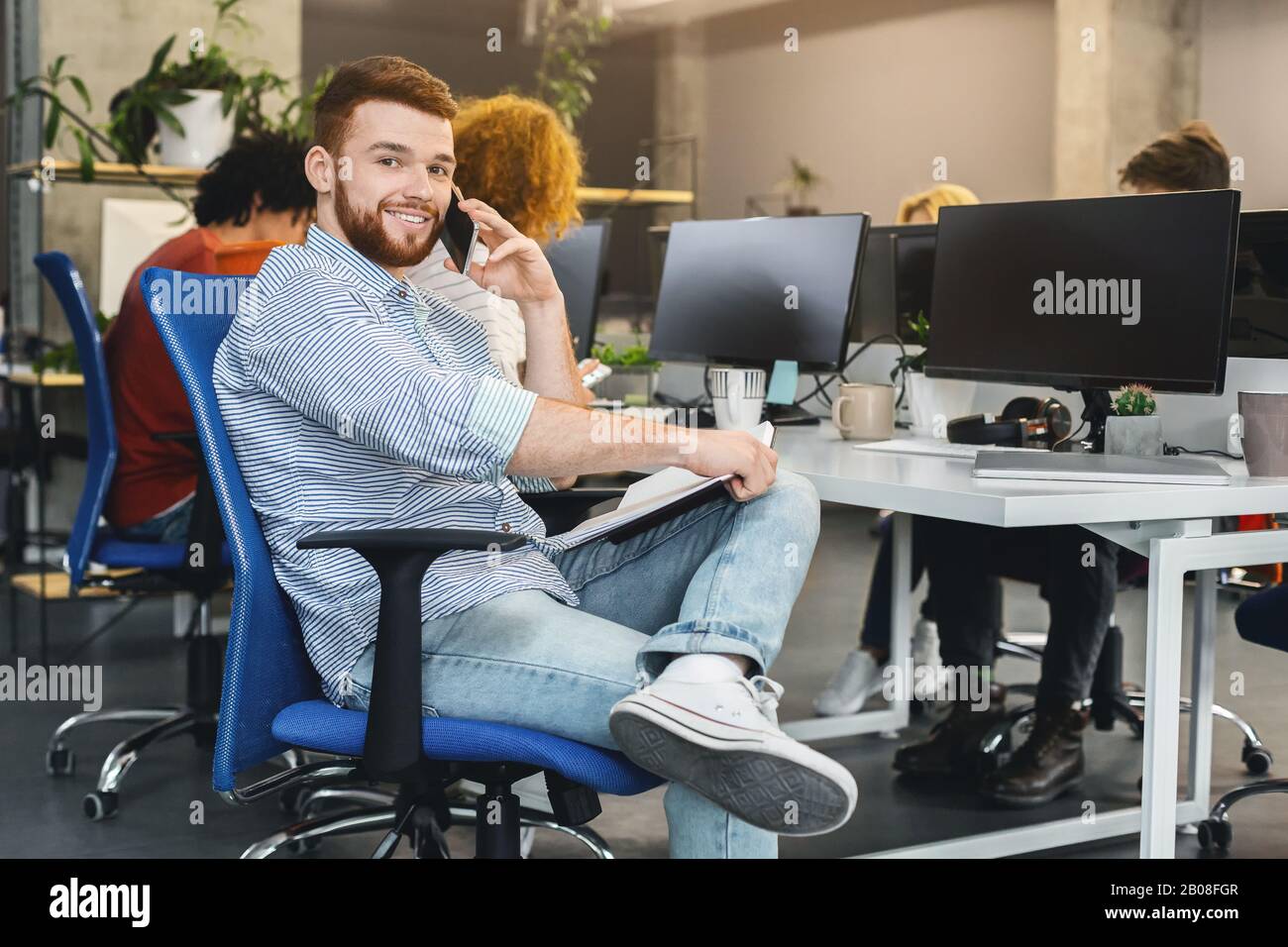 Giovane uomo d'affari che discute le questioni finanziarie con il cliente per telefono Foto Stock