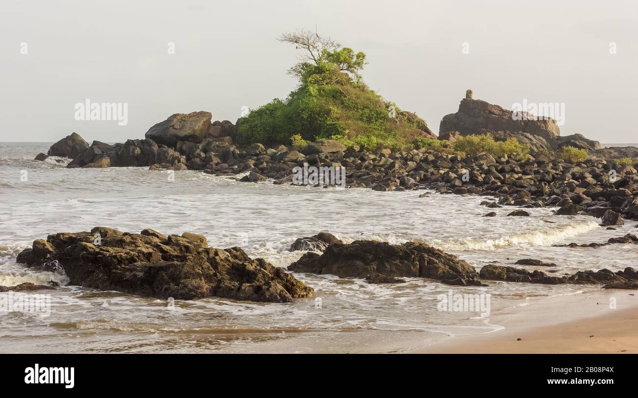 L'idilliaca spiaggia di Om con un piccolo promontorio roccioso che si protende nel mare nel villaggio costiero di Gokarna. Foto Stock