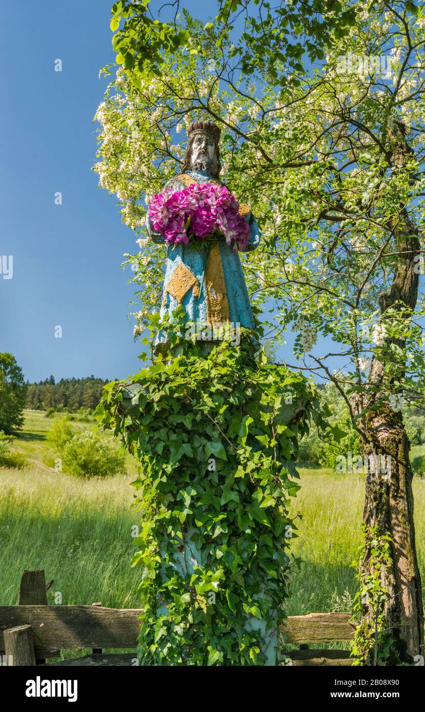 Statua religiosa, fiorendo falso albero di acacia sulla strada vicino al villaggio di Berest, Catena montuosa Di Beskids Inferiore, Carpazi occidentali, Malopolska, Polonia Foto Stock