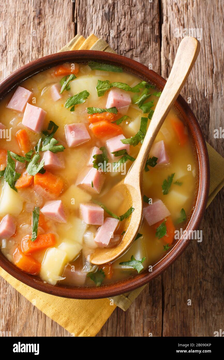 Dividi la zuppa di piselli con verdure e prosciutto da vicino in una ciotola sul tavolo. Vista dall'alto verticale Foto Stock