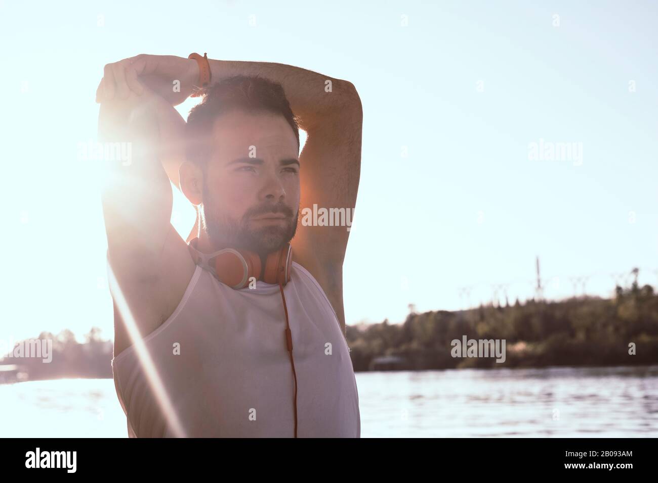 giovane uomo che allunga le braccia con le cuffie. Foto Stock