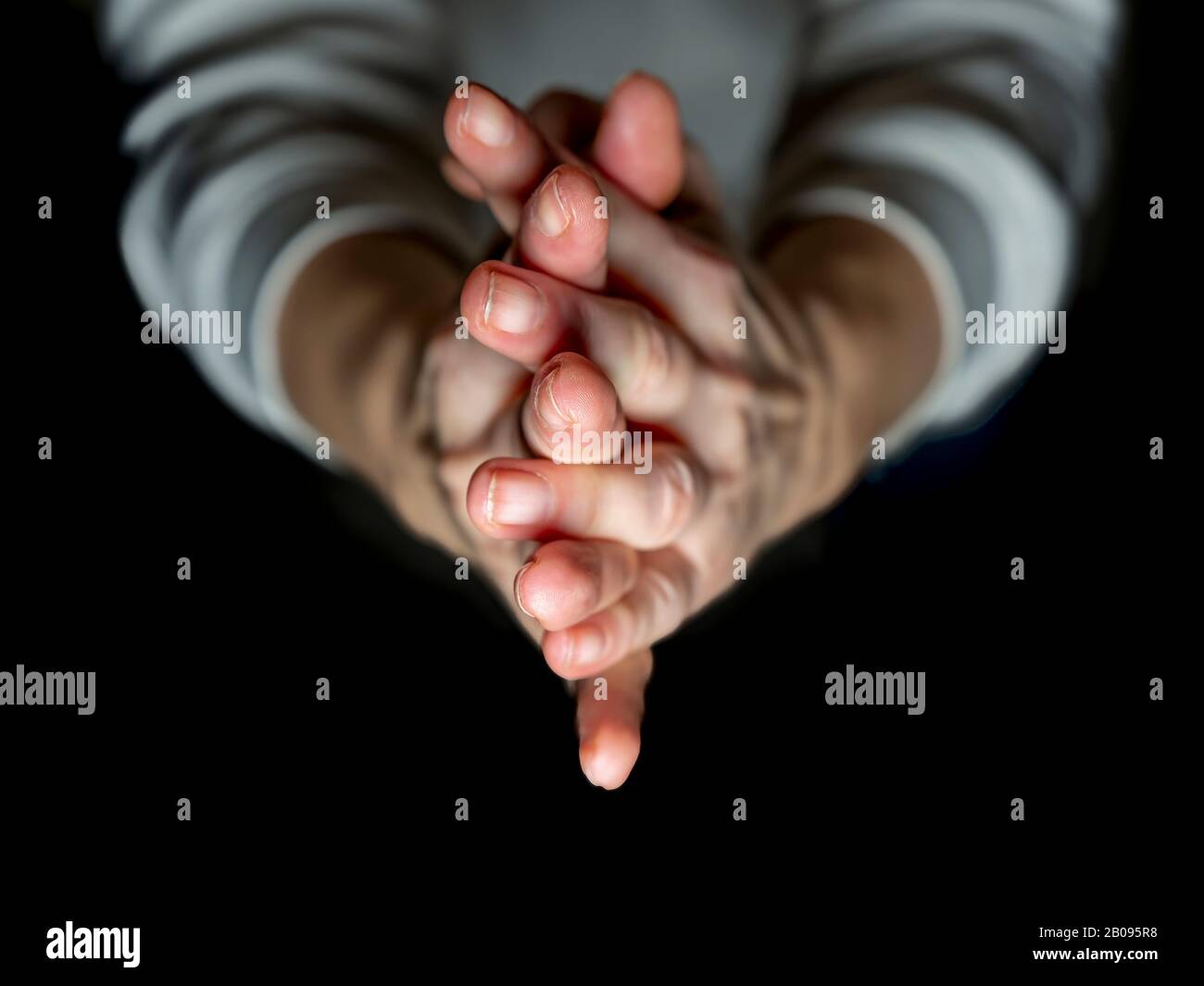 Dettaglio delle mani della donna unite in preghiera su sfondo nero Foto Stock