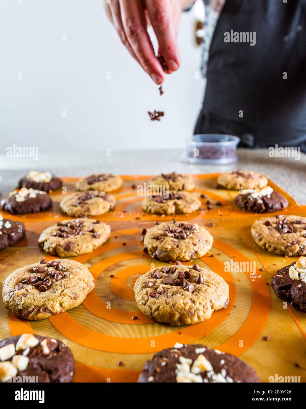 Lo chef rilascia patatine al cioccolato sopra di biscotti appena sfornati Foto Stock