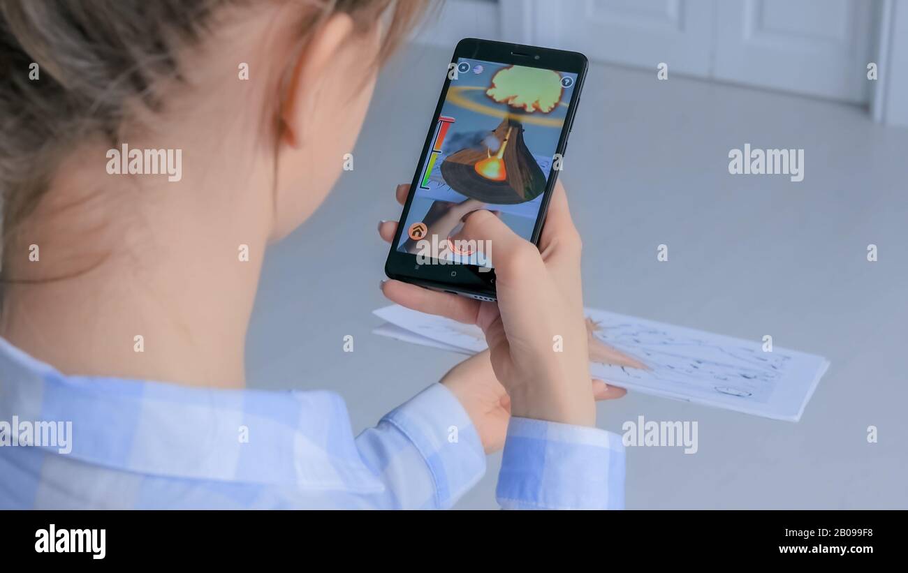Donna che utilizza uno smartphone con applicazione AR - eruzione vulcanica virtuale Foto Stock